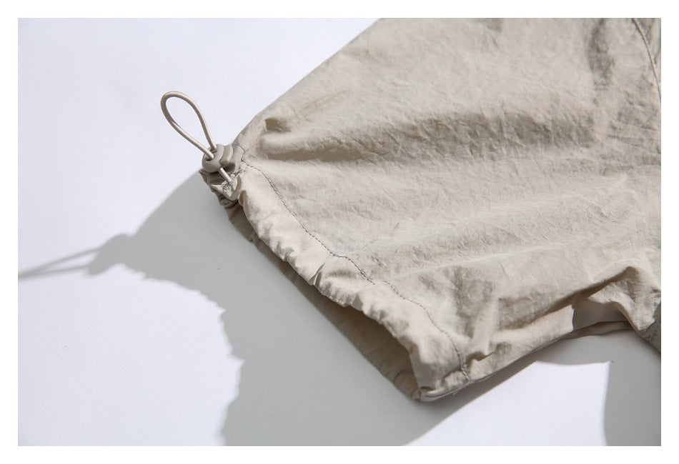 Close-up of a beige jacket edge with an elastic drawcord loop and toggle.