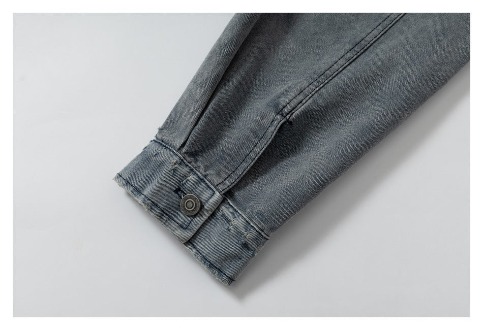 Close-up of a faded blue-gray denim cuff with double stitching and a metal button.