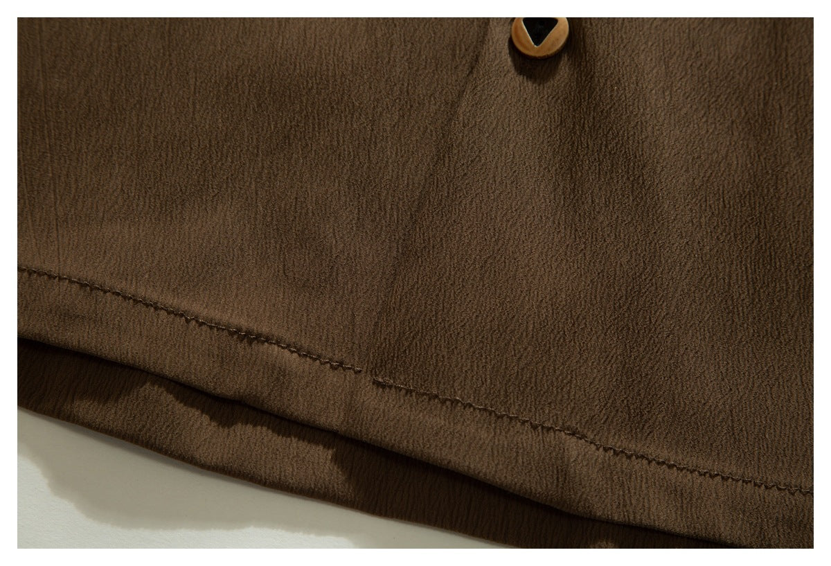 Close-up of a brown garment hem with visible stitching and part of a button.
