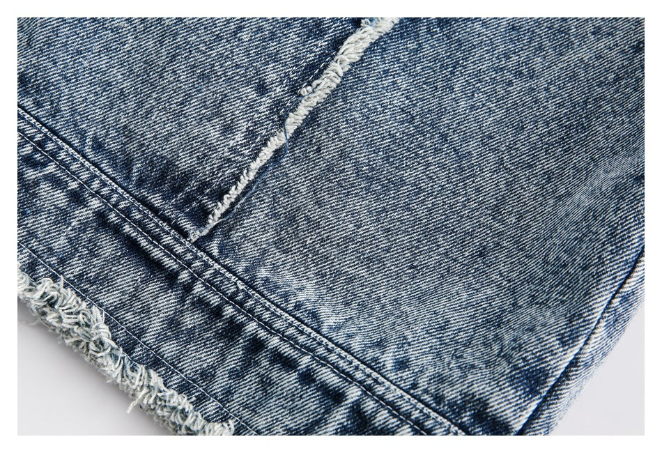 Close-up of blue acid-wash denim with parallel stitched seams and a frayed edge.