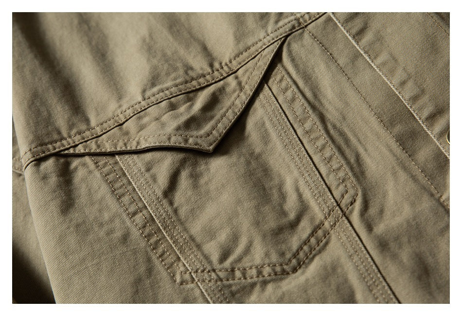 Close-up of a flap pocket with reinforced stitching on an olive-khaki garment.