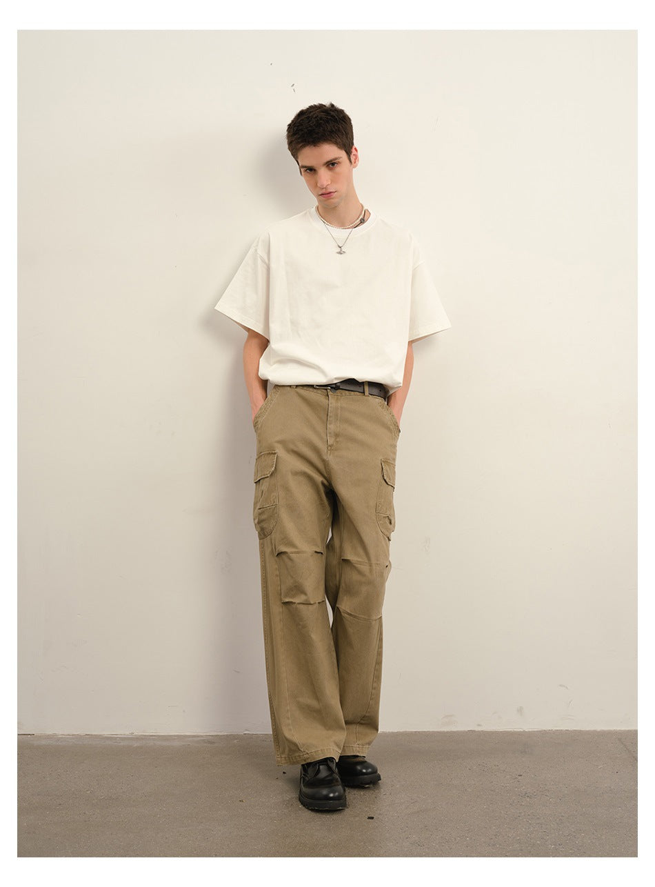 Front view of a model wearing khaki wide-leg cargo pants with flap pockets, a white T-shirt and black shoes.