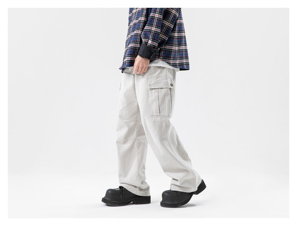 Side view of a model wearing loose light gray cargo pants with a flap thigh pocket and black shoes.