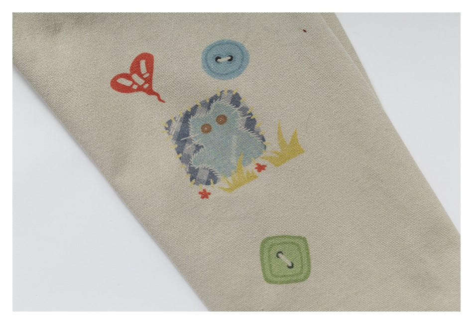 Close-up of a beige sleeve with a colorful hedgehog illustration and button motifs.