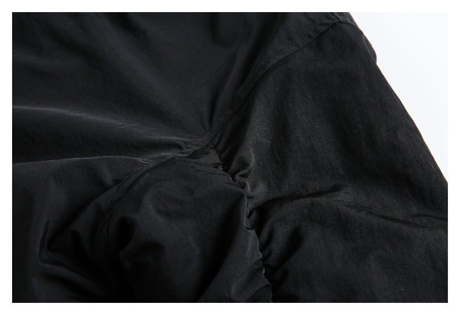 Close-up of black garment fabric showing a curved stitched seam and gathered section.