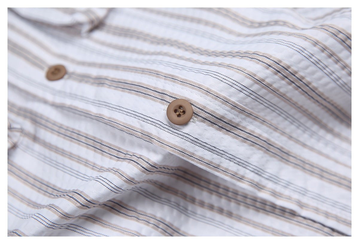 Close-up of brown buttons and fine gray and beige stripes on a white shirt.