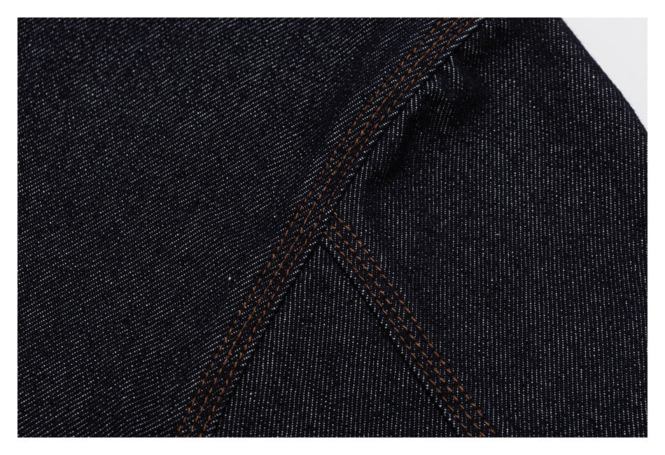 Close-up of a curved seam with double orange topstitching on dark indigo denim.