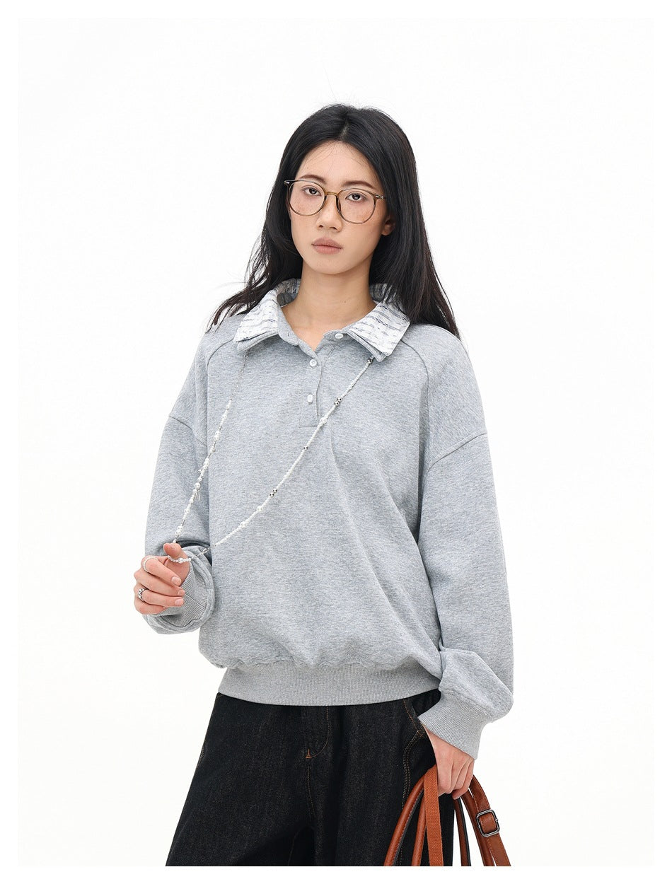 Front view of a model in a light gray oversized pullover with a striped collar and ribbed cuffs and hem.
