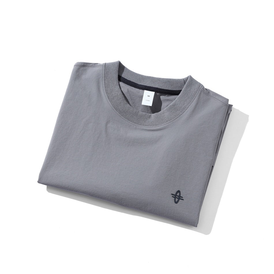 Folded gray crewneck shirt showing its front, ribbed collar, and small dark emblem.