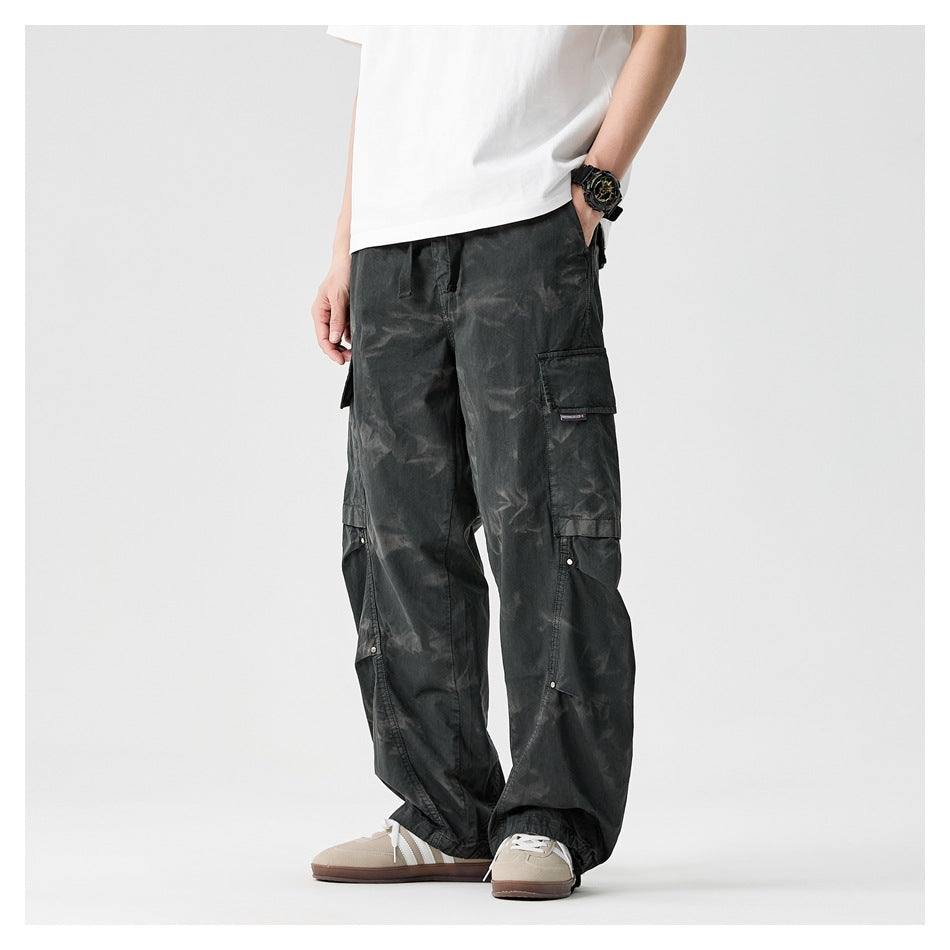 Front view of a model wearing loose charcoal cargo pants with flap pockets and gathered ankle cuffs.