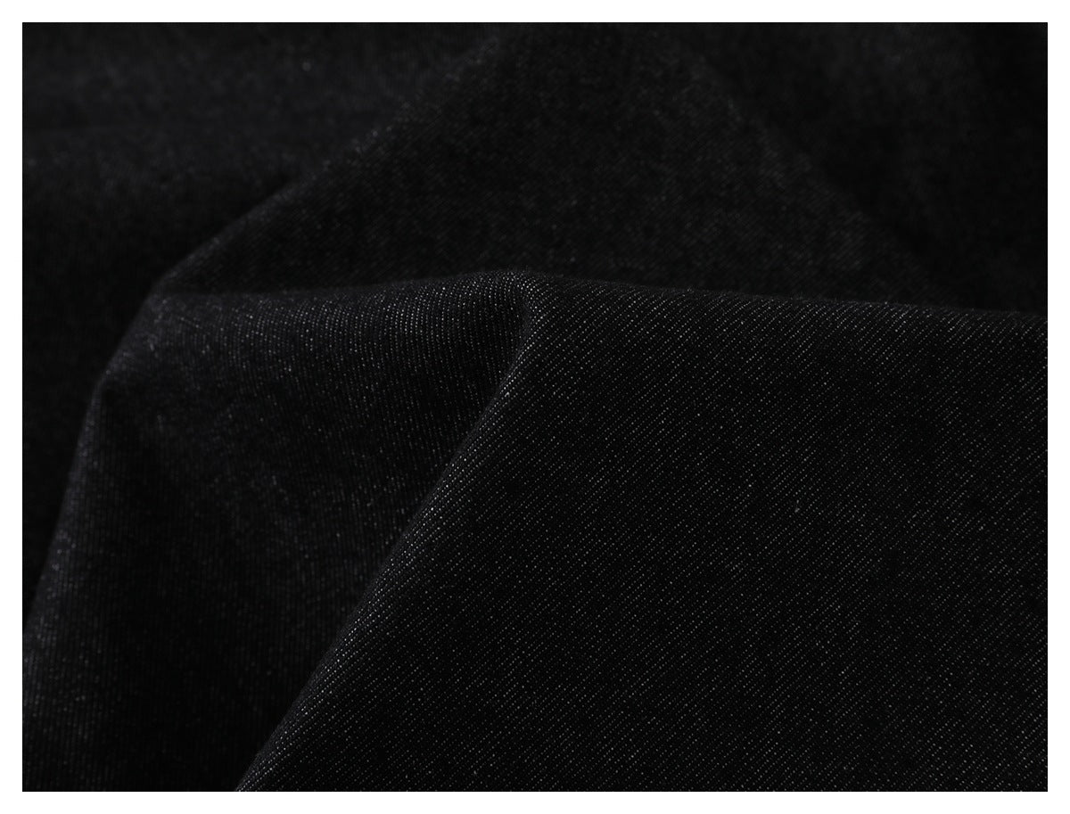Close-up of folded dark denim fabric showing its diagonal weave and texture.