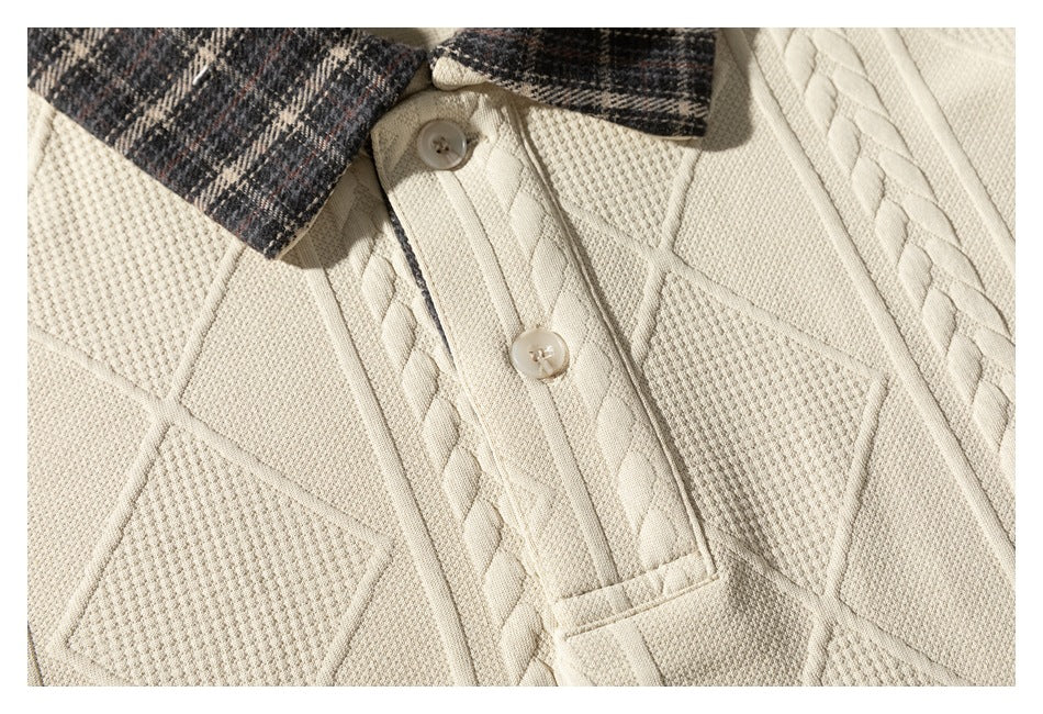 Close-up of the cream sweater's two-button placket, plaid collar, and raised cable and diamond-knit details.