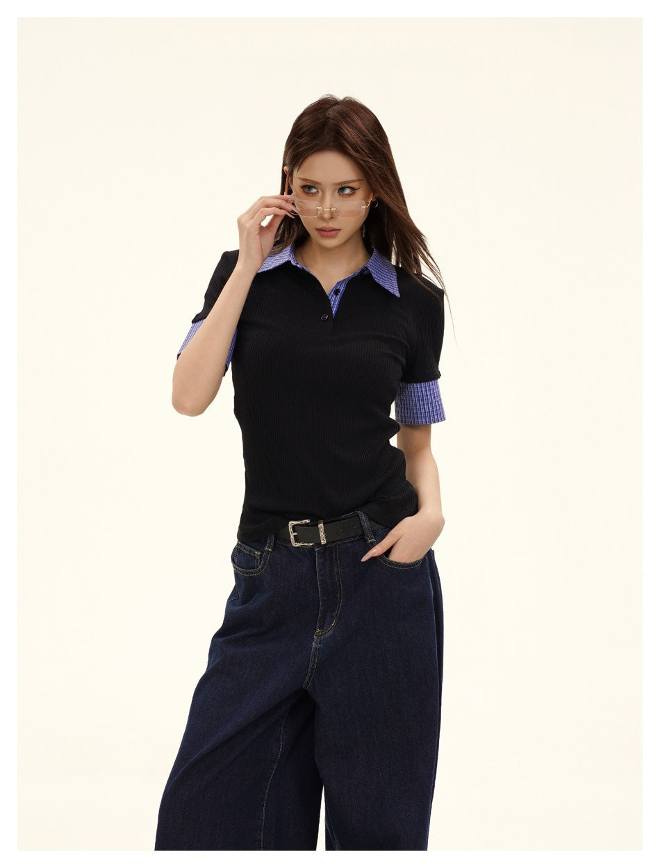 Closer front view of a model wearing a black ribbed polo with blue check collar and sleeve cuffs.