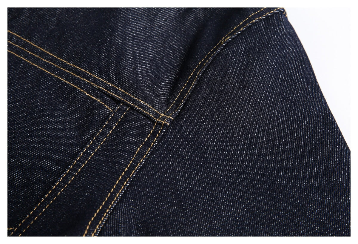 Close-up of dark indigo denim panels joined with parallel gold stitching.