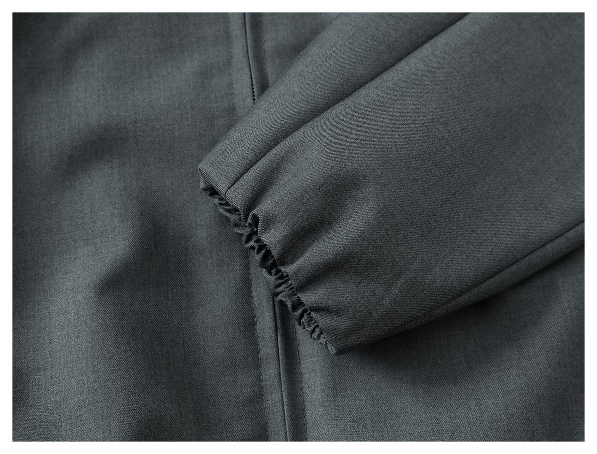 Close-up of charcoal-gray garment fabric showing a gathered edge and stitched seams.