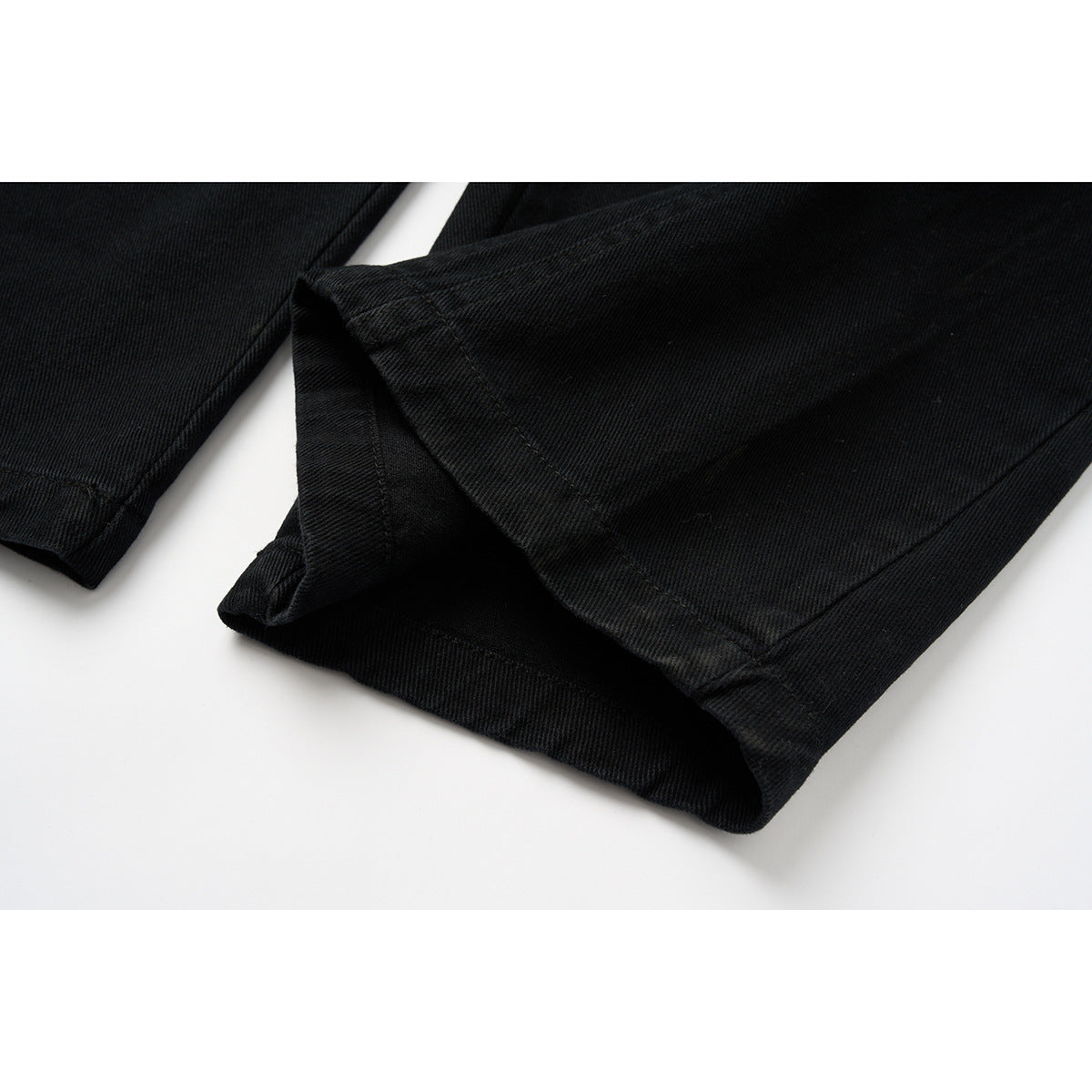 Close-up of the black pants legs and stitched hems.