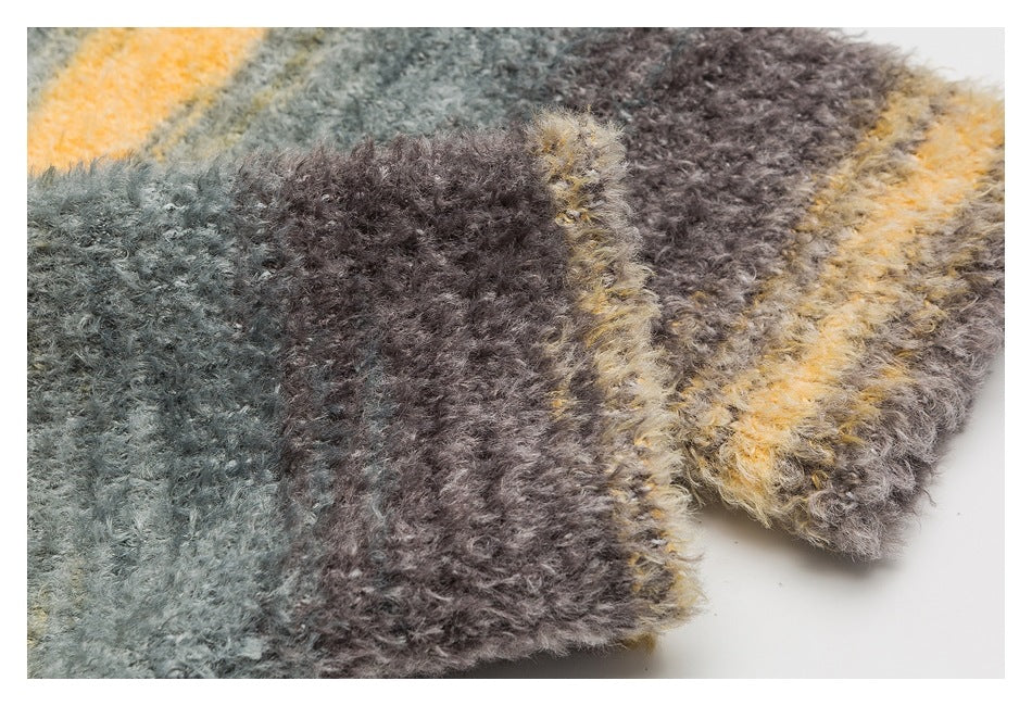 Close-up of a fuzzy sweater edge with gray, brown, and mustard striped knit.