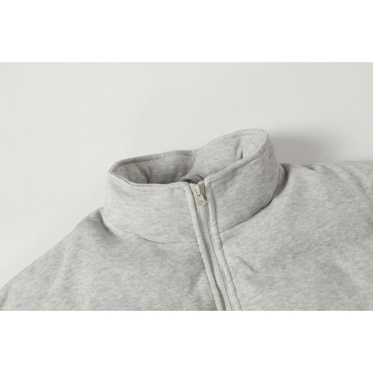 Close-up of a light gray heather jacket's tall stand collar and front zipper.