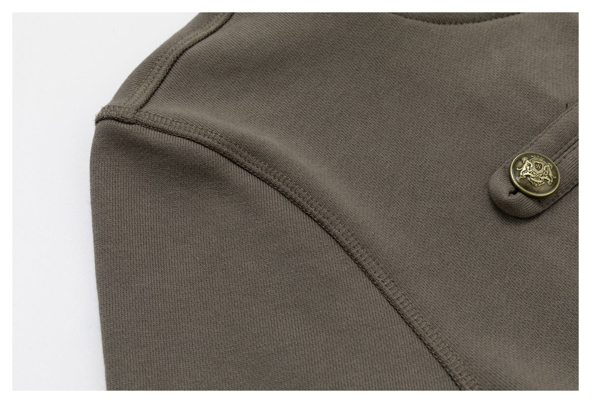 Close-up of an olive-brown garment shoulder seam and a decorative brass-colored button.
