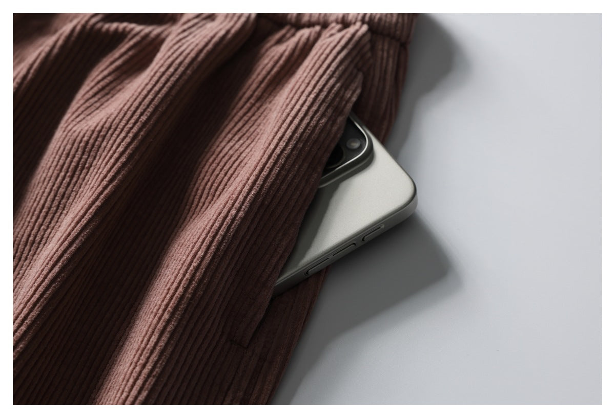 Close-up of a pocket in dusty rose ribbed trousers, with a phone partly tucked inside.