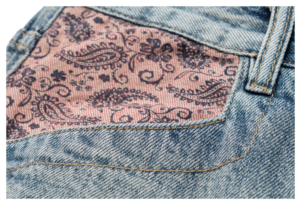 Close-up of a denim pocket lined with pink fabric printed with a dark paisley and floral pattern.