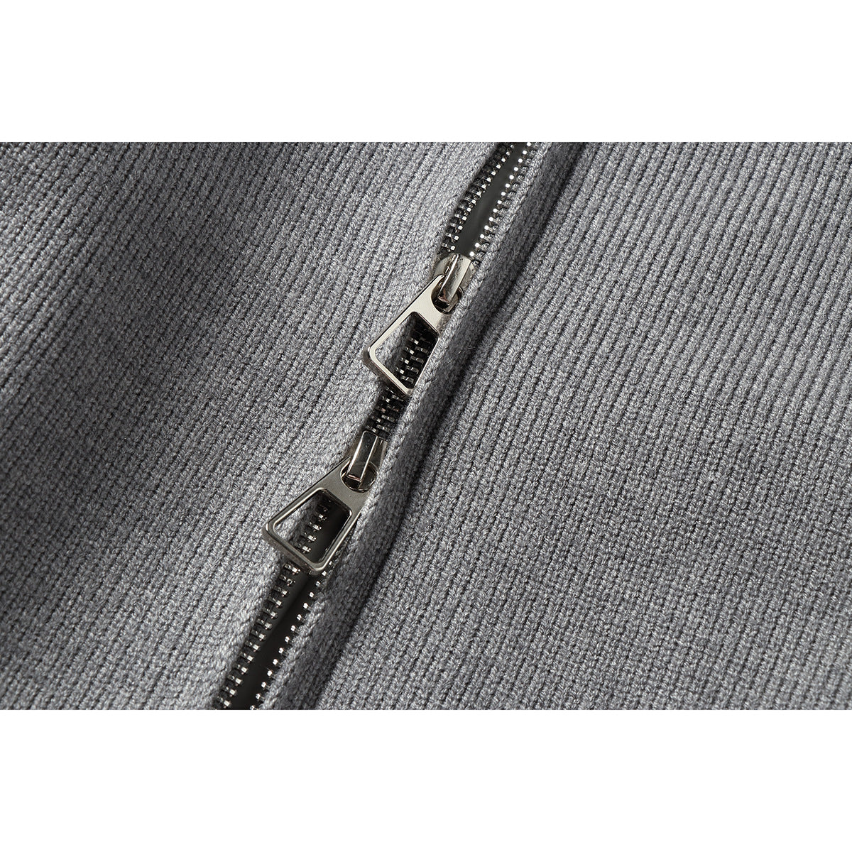 Close-up of two silver zipper pulls on the gray rib-knit jacket.
