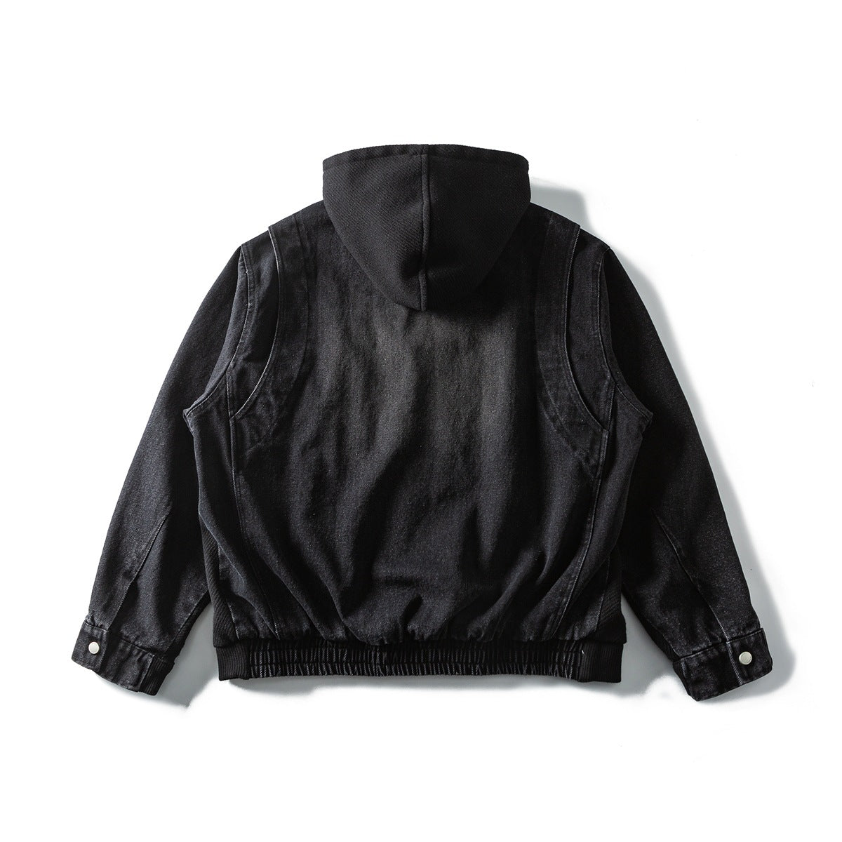 Back view of a black hooded jacket laid flat, with long sleeves, snap cuffs, and a ribbed hem.