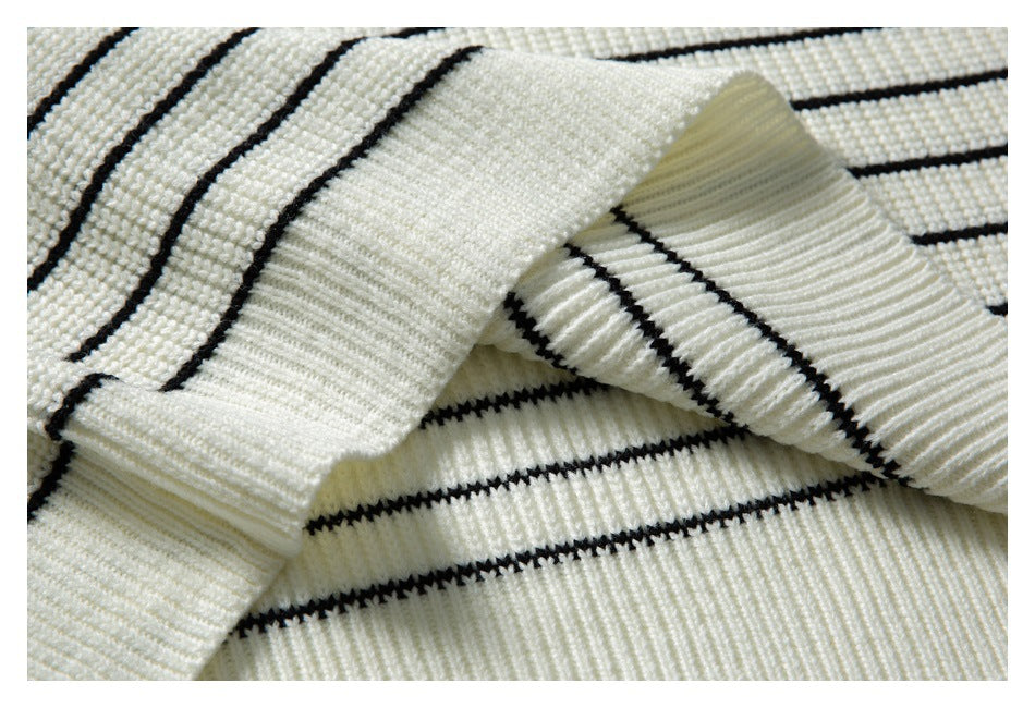 Close-up of an ivory knit garment with narrow black stripes and a ribbed edge.