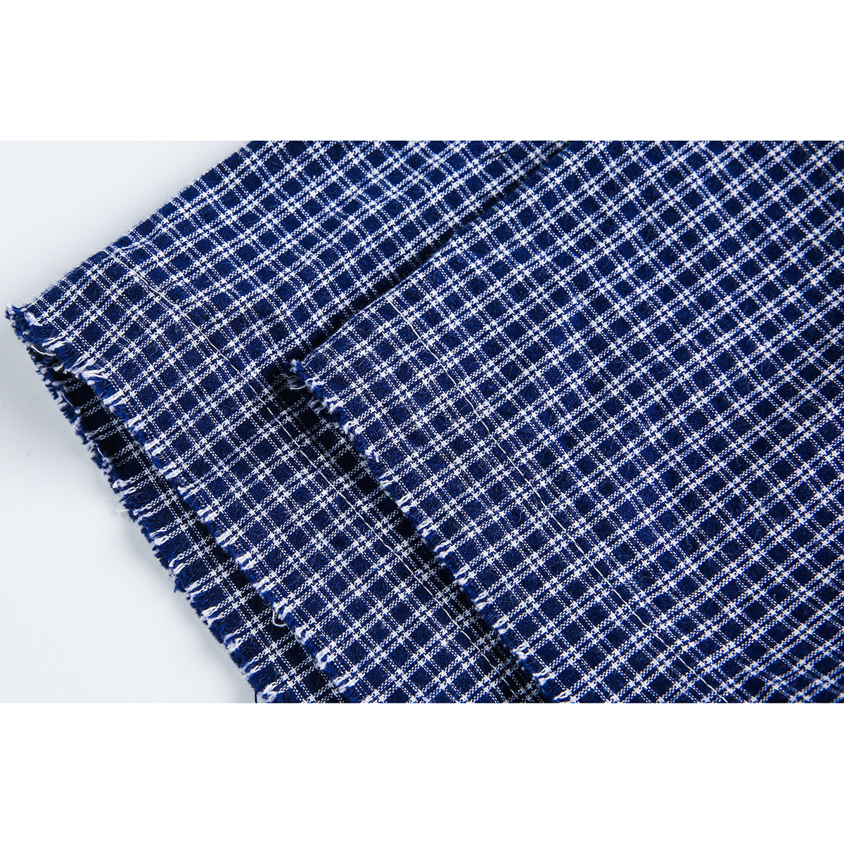 Close-up of the frayed edge and checked weave of navy-and-white shirt fabric.