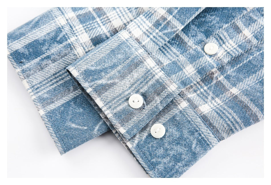 Close-up of a blue and white plaid shirt cuff with three white buttons.
