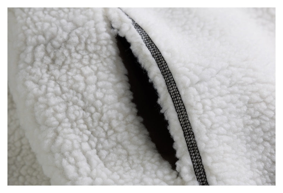 Close-up of a dark-edged pocket opening and overlock stitching on the ivory sherpa jacket.