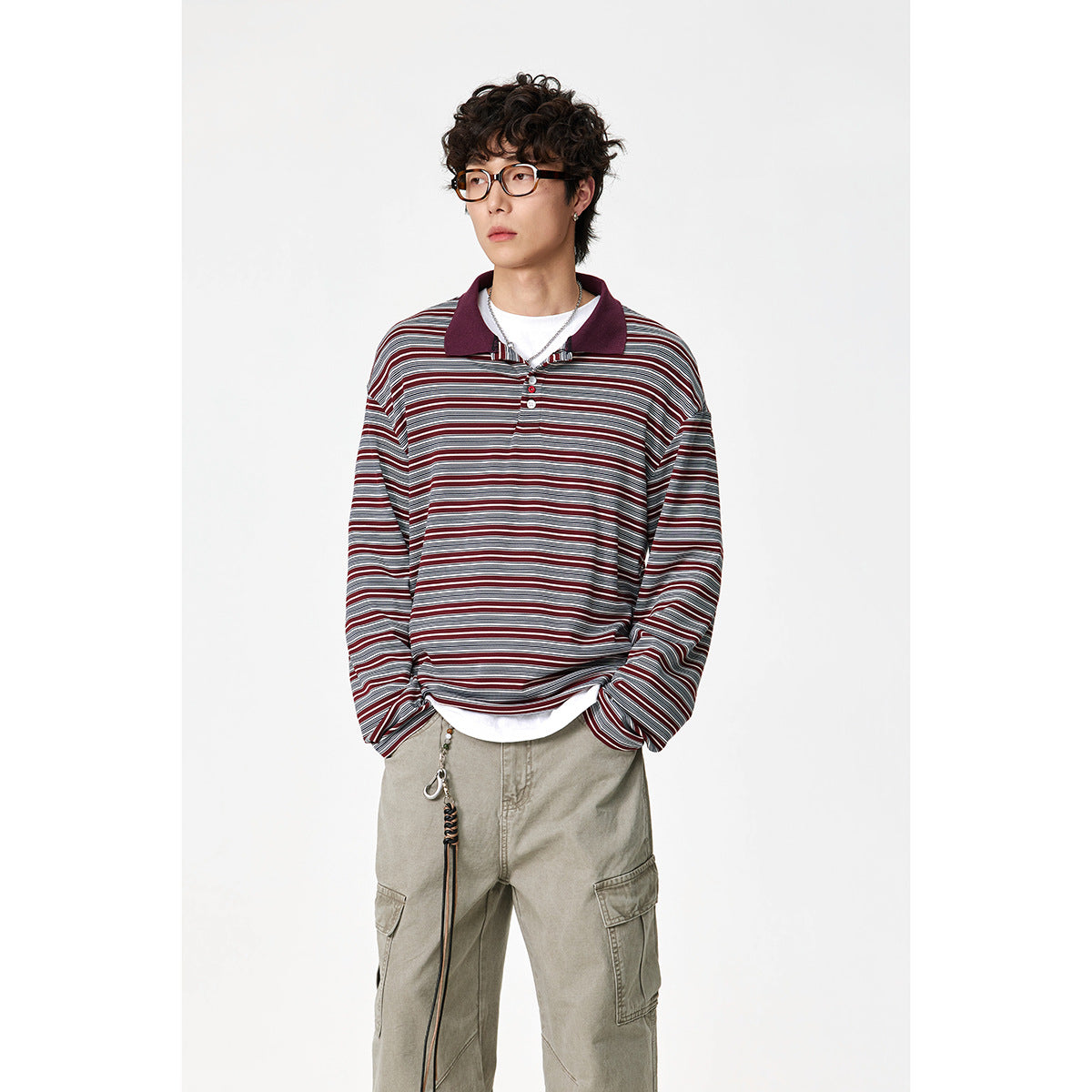 Model wearing a burgundy, gray and white striped long-sleeve polo with a dark burgundy collar and khaki cargo pants.