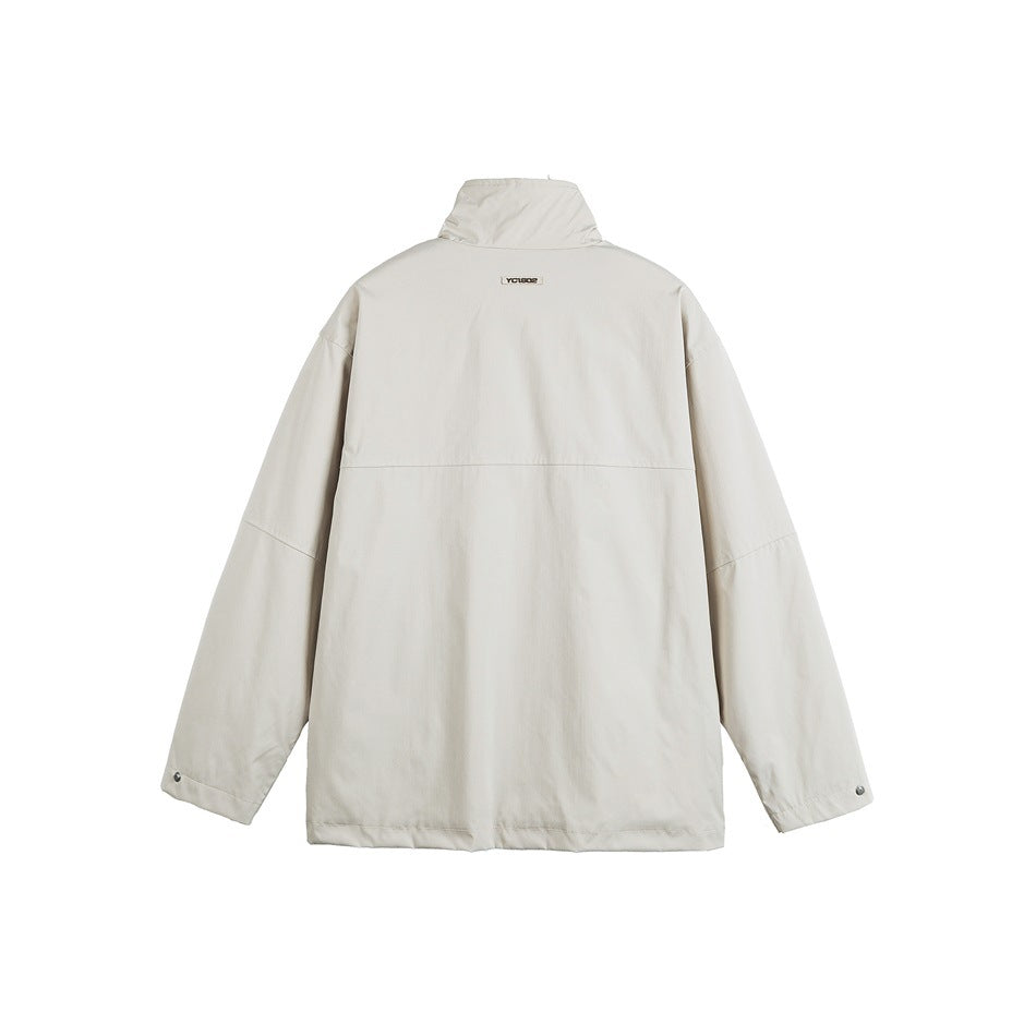 Back view of a light beige jacket with a raised collar, long sleeves, and snap cuffs.