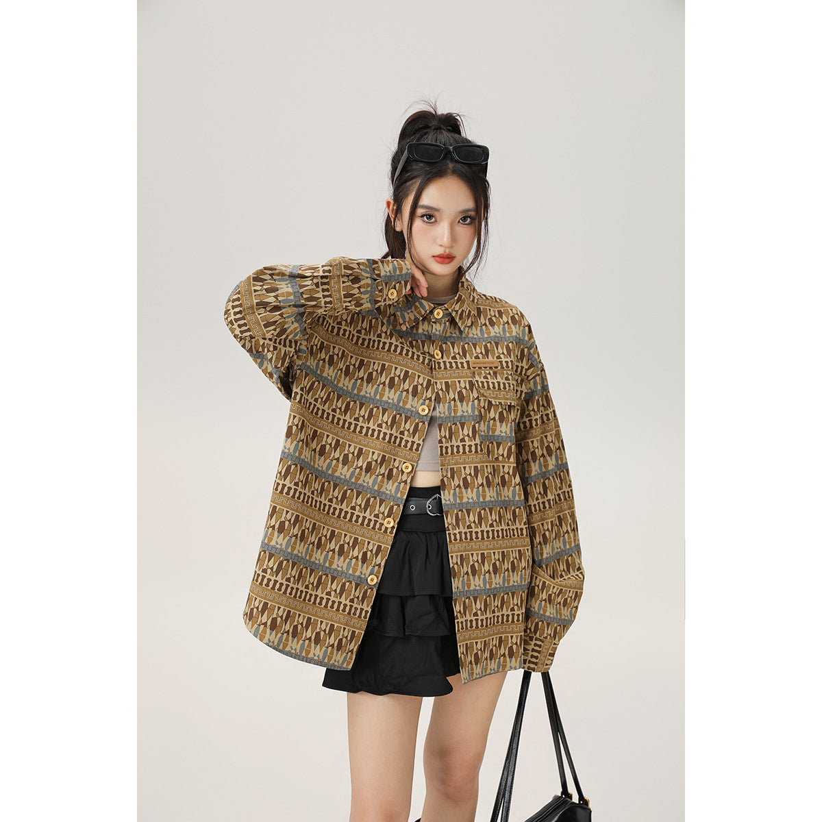 Model wearing an oversized brown geometric-pattern button-up jacket with blue-gray stripe accents, front view.