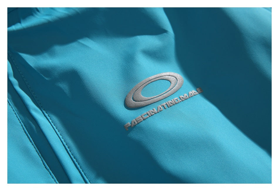 Close-up of a silver oval emblem and embroidered lettering on turquoise jacket fabric.