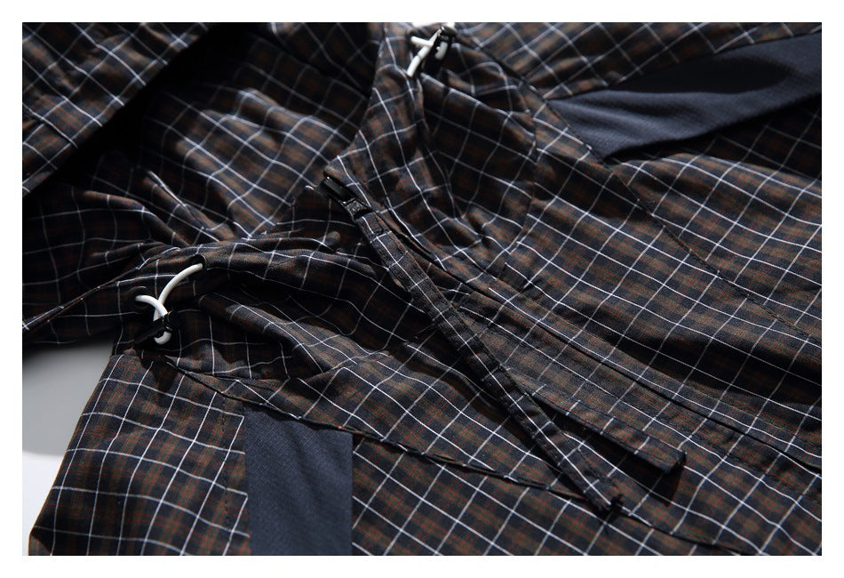 Close view of plaid jacket fabric, white hood drawcords, and a dark trim panel.