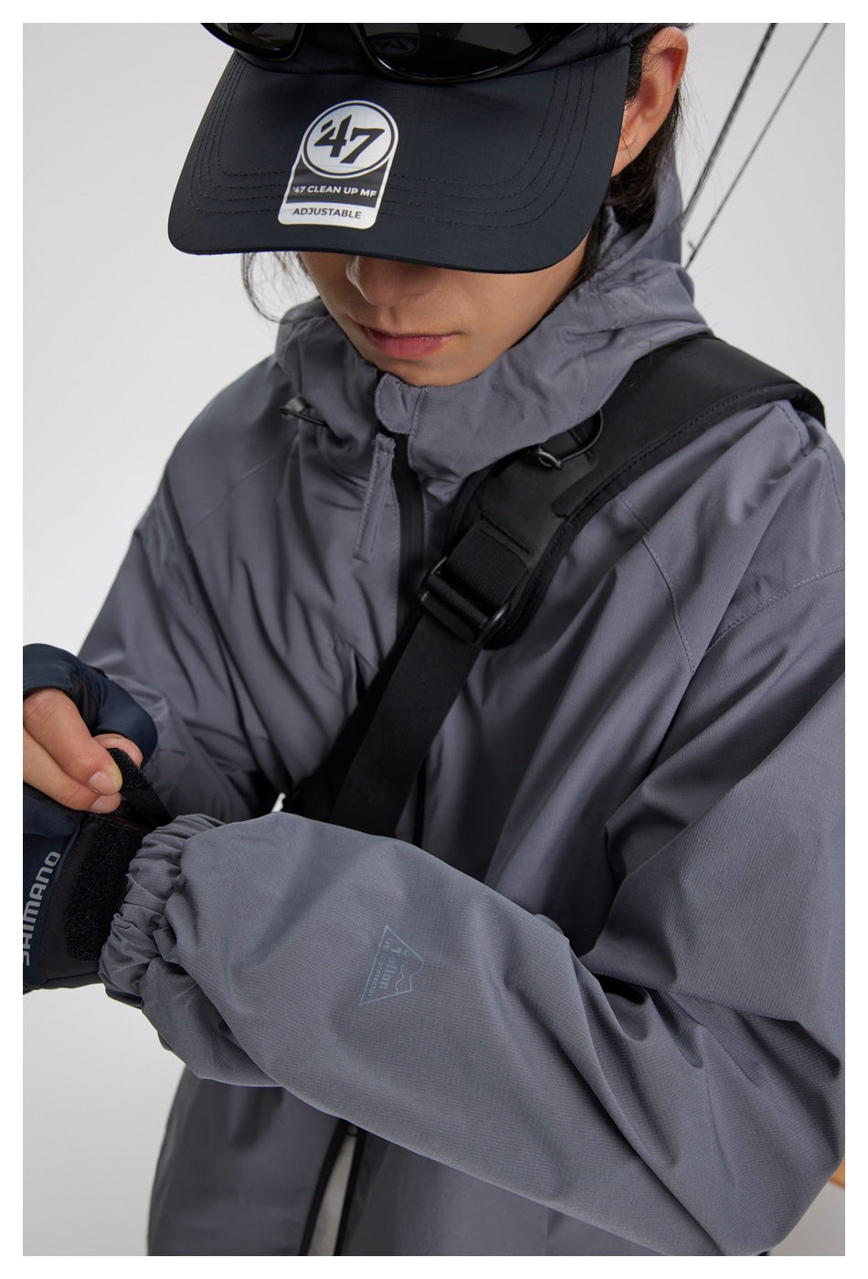 Close-up of a person wearing a gray hooded jacket with elastic cuffs and a small sleeve emblem.