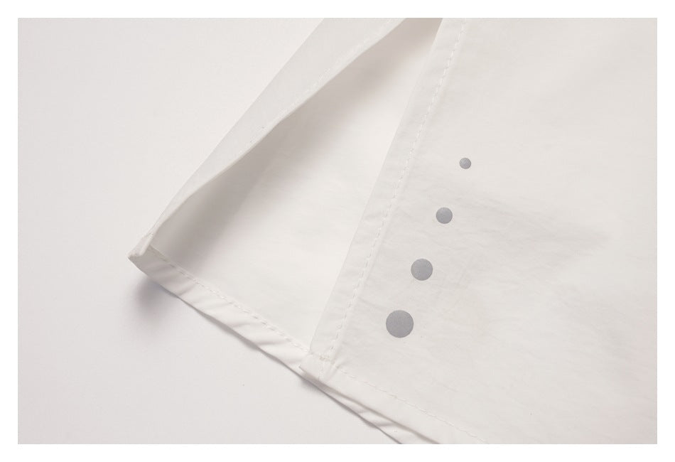 Close-up of white garment fabric with a stitched edge and four gray circular fasteners.