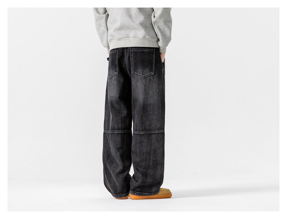 Smaller inset rear view of a model in loose black washed jeans with back pockets and horizontal leg seams.