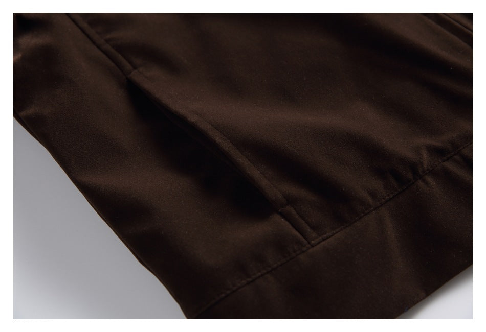 Close-up of a dark brown jacket's lower front, showing a pocket opening, seams, and hem.