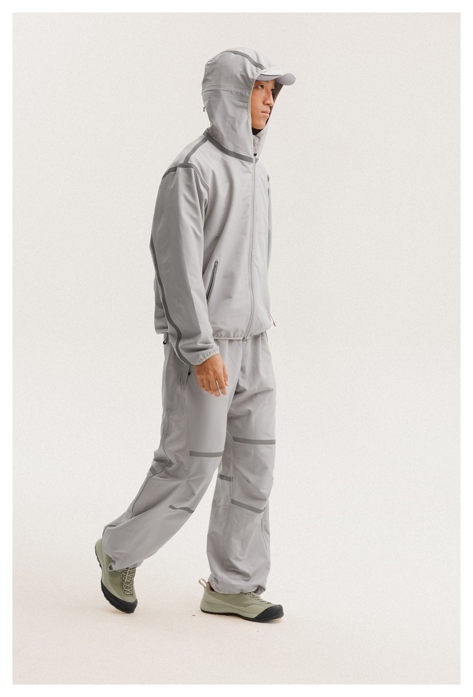 Side view of a model wearing a light gray hooded jacket with darker trim and matching pants.