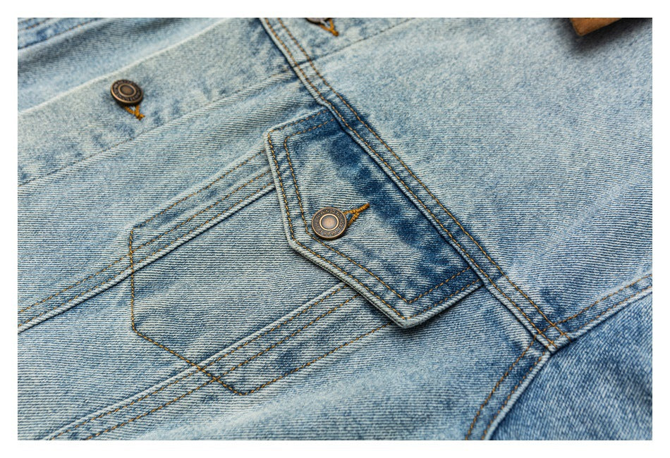 Close-up of light blue denim jacket stitching, a flap pocket, and metal buttons.