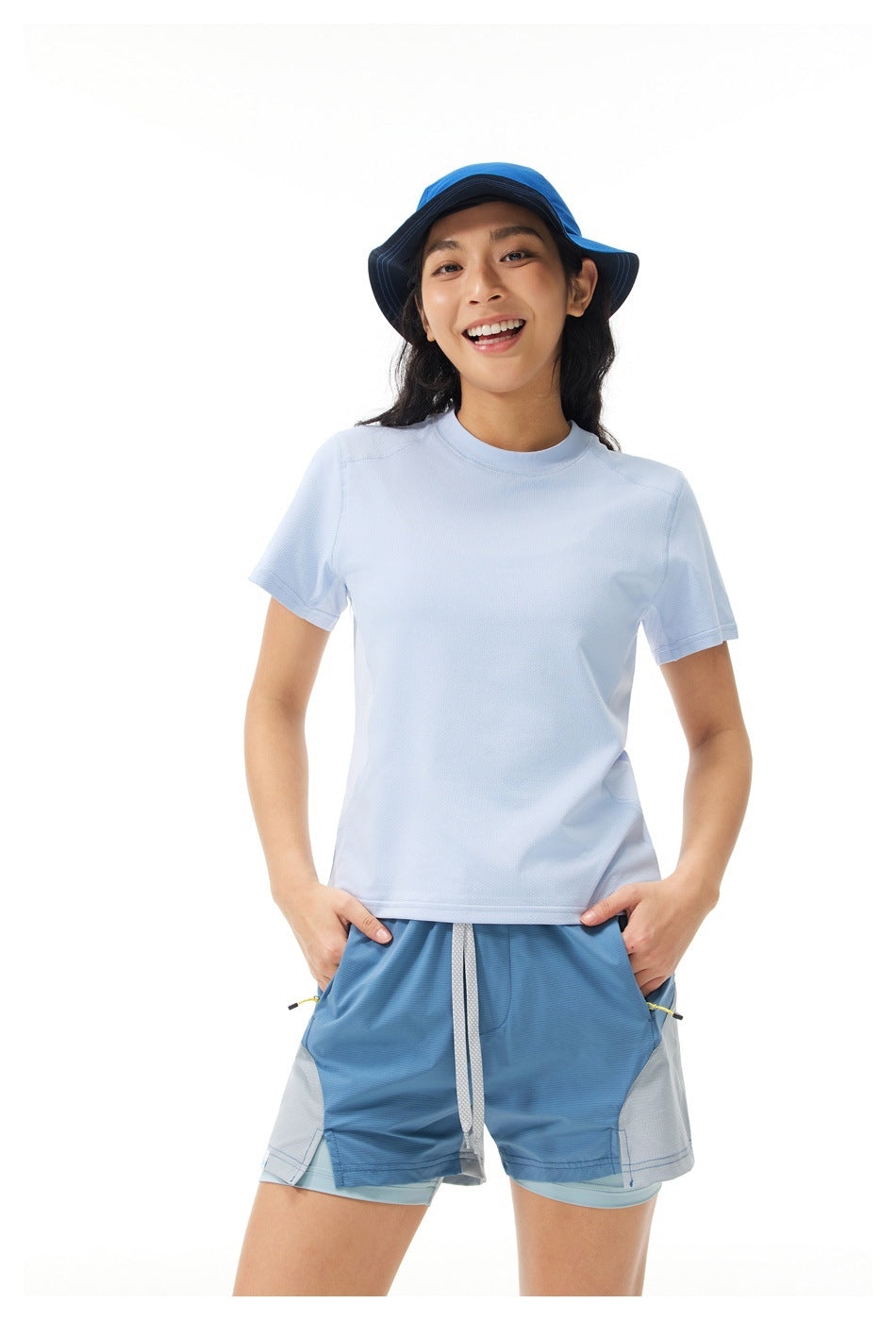 Woman in a light blue short-sleeve crew-neck T-shirt with a blue bucket hat and blue shorts