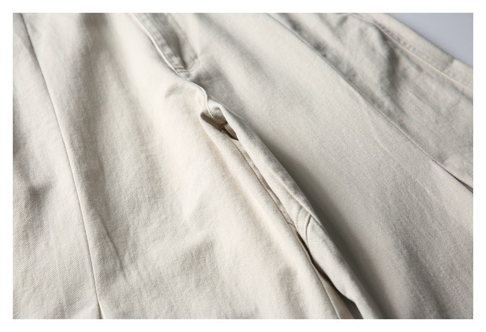 Close-up of light beige trousers showing a slanted pocket opening and stitched seams.