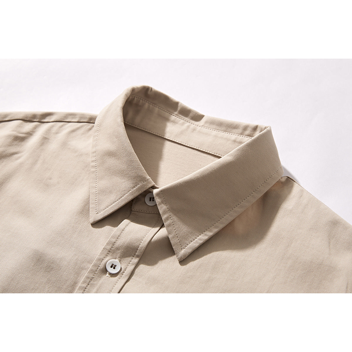 Close-up of a beige button-up shirt collar and upper placket with white buttons.