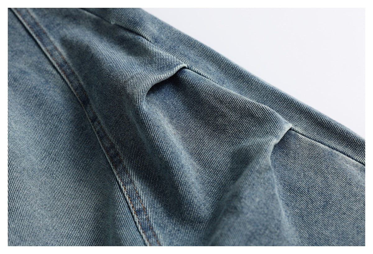 Close-up of blue denim with a raised fold and diagonal seam with brown stitching.