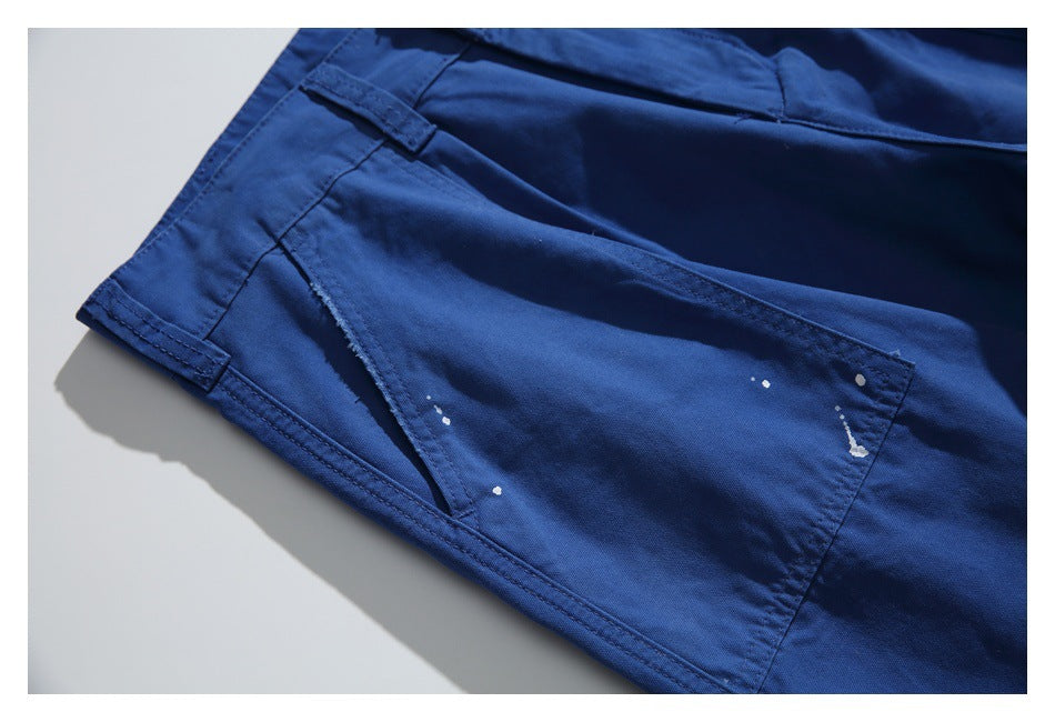 Close-up of a cobalt-blue trouser pocket with visible stitching and scattered white paint-like marks.