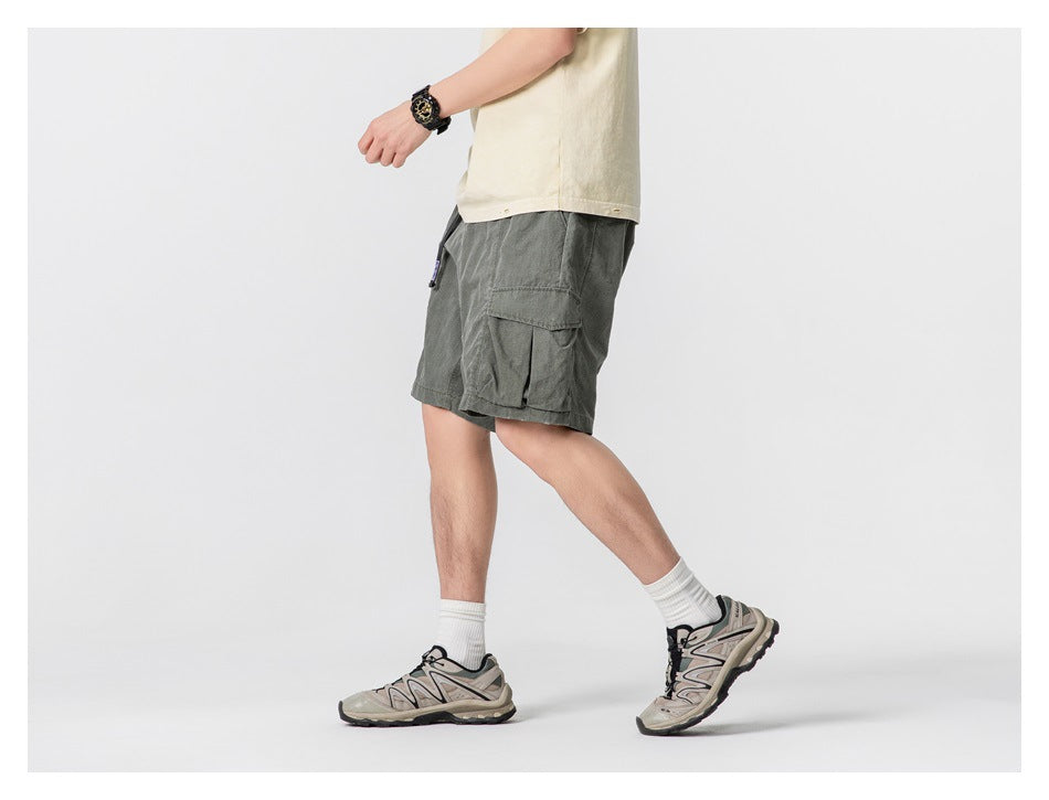 Side view of a model wearing dark gray-green cargo shorts with a large flap pocket.