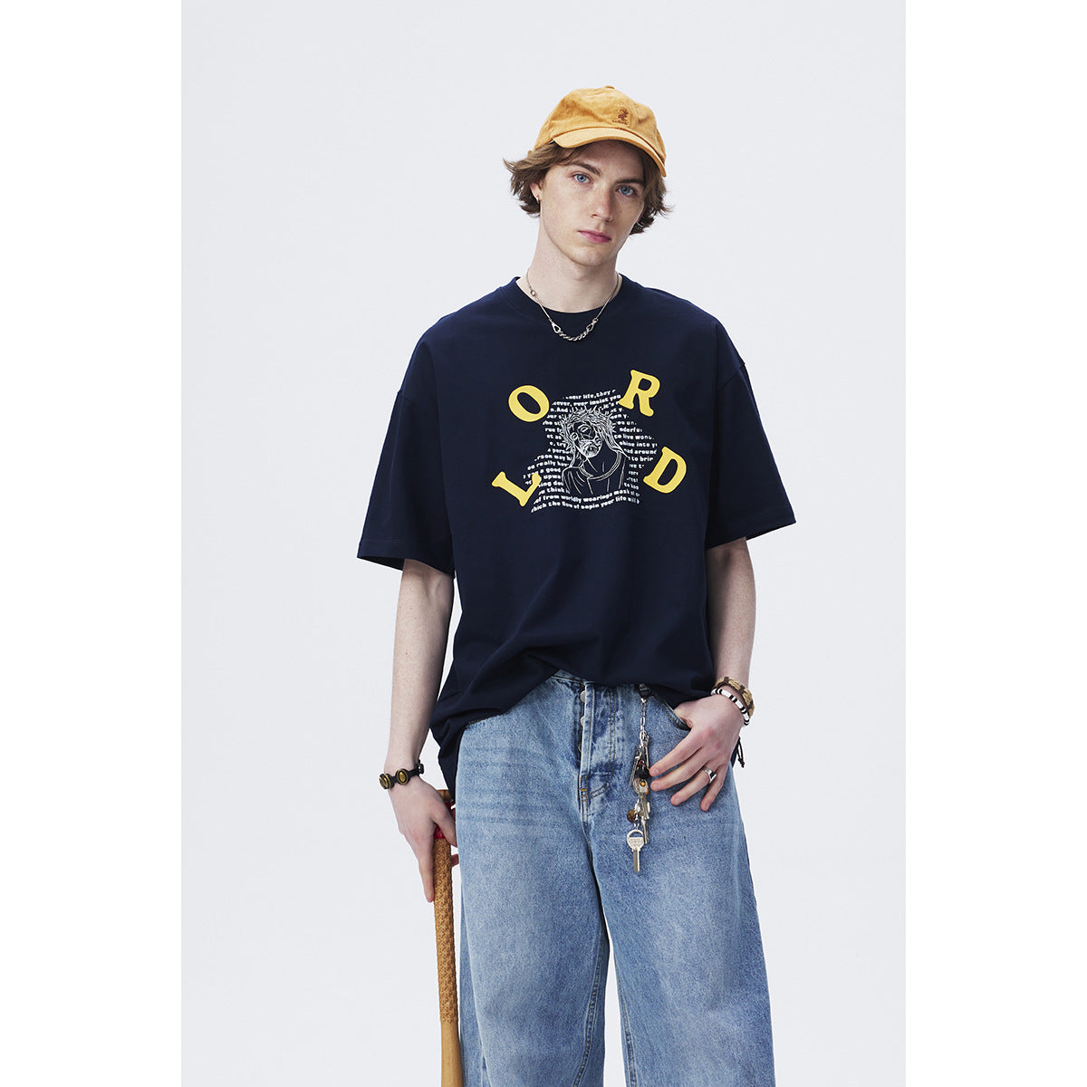 Closer view of a model in a navy T-shirt with yellow lettering and a central illustrated graphic.