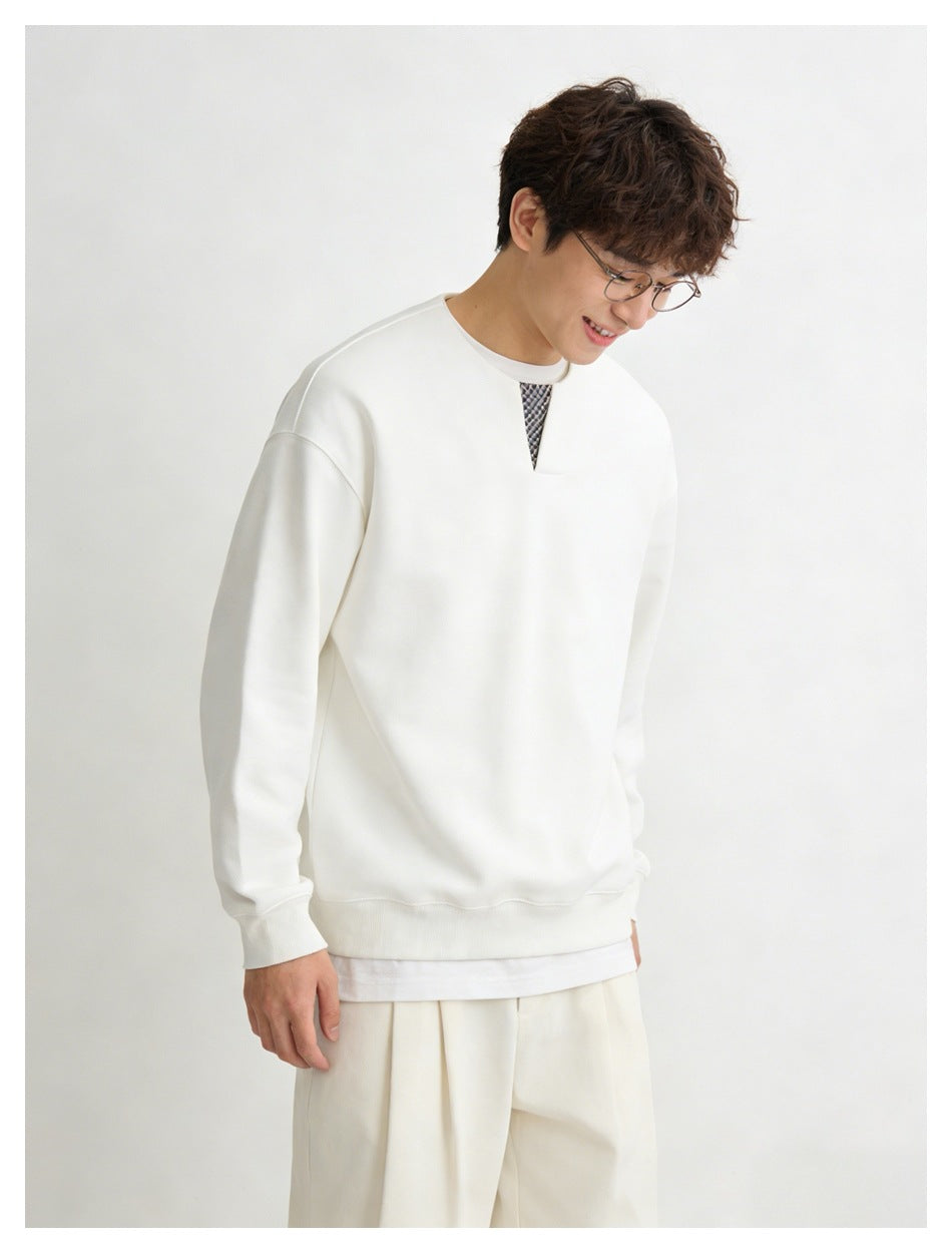 Model wearing a white sweatshirt with a checked V-shaped neckline insert and matching trousers, shown at an angle.